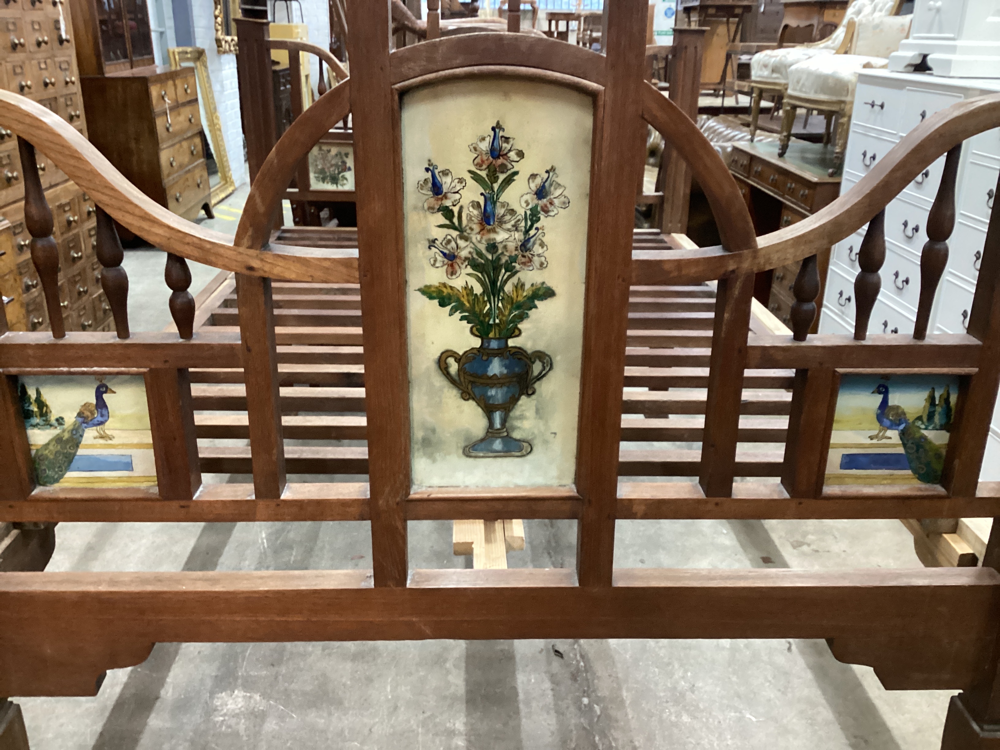 A 19th century Zanzibar hardwood bedframe inset reverse painted glass panels of peacocks and vases of flowers, length 210cm, width 140cm, height 215cm